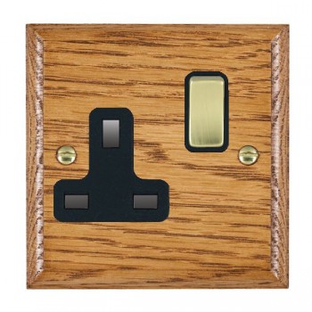Hamilton Woods Ovolo Medium Oak 1 Gang 13A Double Pole Switched Socket with Polished Brass Rocker and Black Surround