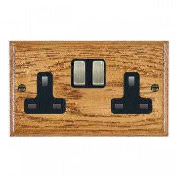 Hamilton Woods Ovolo Medium Oak 2 Gang 13A Double Pole Switched Socket with Antique Brass Rockers and Black Surround